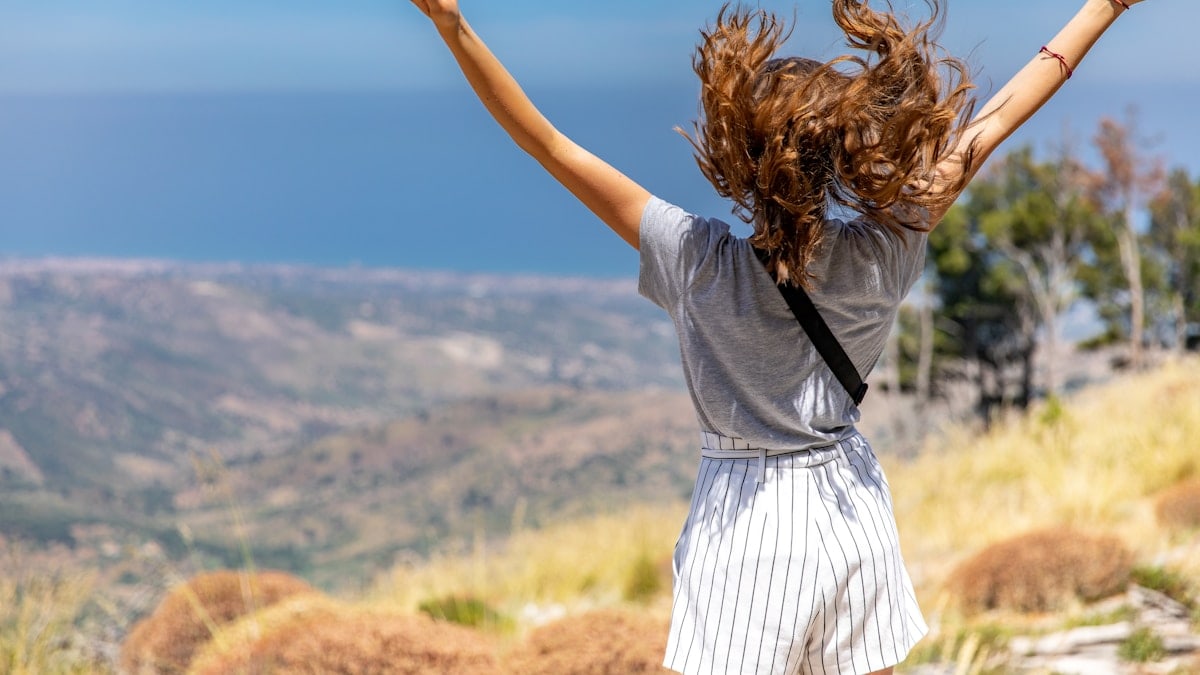 a woman with her hair in the air on top of a hill